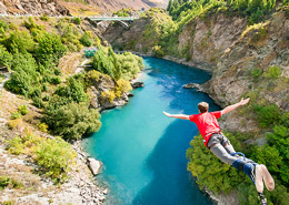 Joven practicando bungee jumping en medio de las montañas