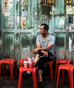 Hombre asiatico sentado en una banca roja