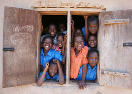 Imagen de niños africanos asomados en una ventana sonriendo