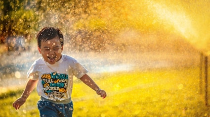 Niño jugando en rociadores de agua | Colombian Tourist