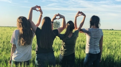 Grupo de 4 amigas haciendo corazones con las manos | Colombian Tourist