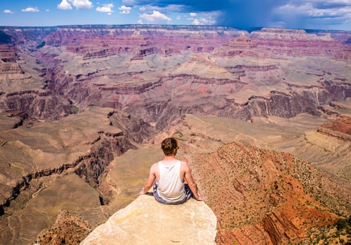 Hombre sentado en la orilla de un acantilado en el Gran Canyon