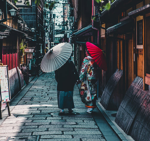 Fotografia de dos mujeres japonesas caminando con sus sombrillas por las calles de japon
